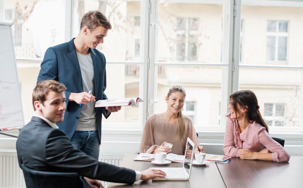 Young insurance professionals discussing CISR designation training in a modern office setting. A team collaborates on Certified Insurance Service Representative certification courses, improving customer service skills.